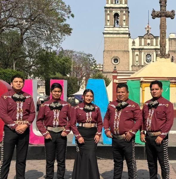 Cinco integrantes del mariachi con camisa guinda bordada frente a una iglesia de Cuautitlán