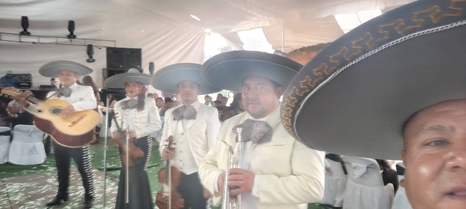 Mariachi con traje claro y sombrero charro durante un evento especial con invitados