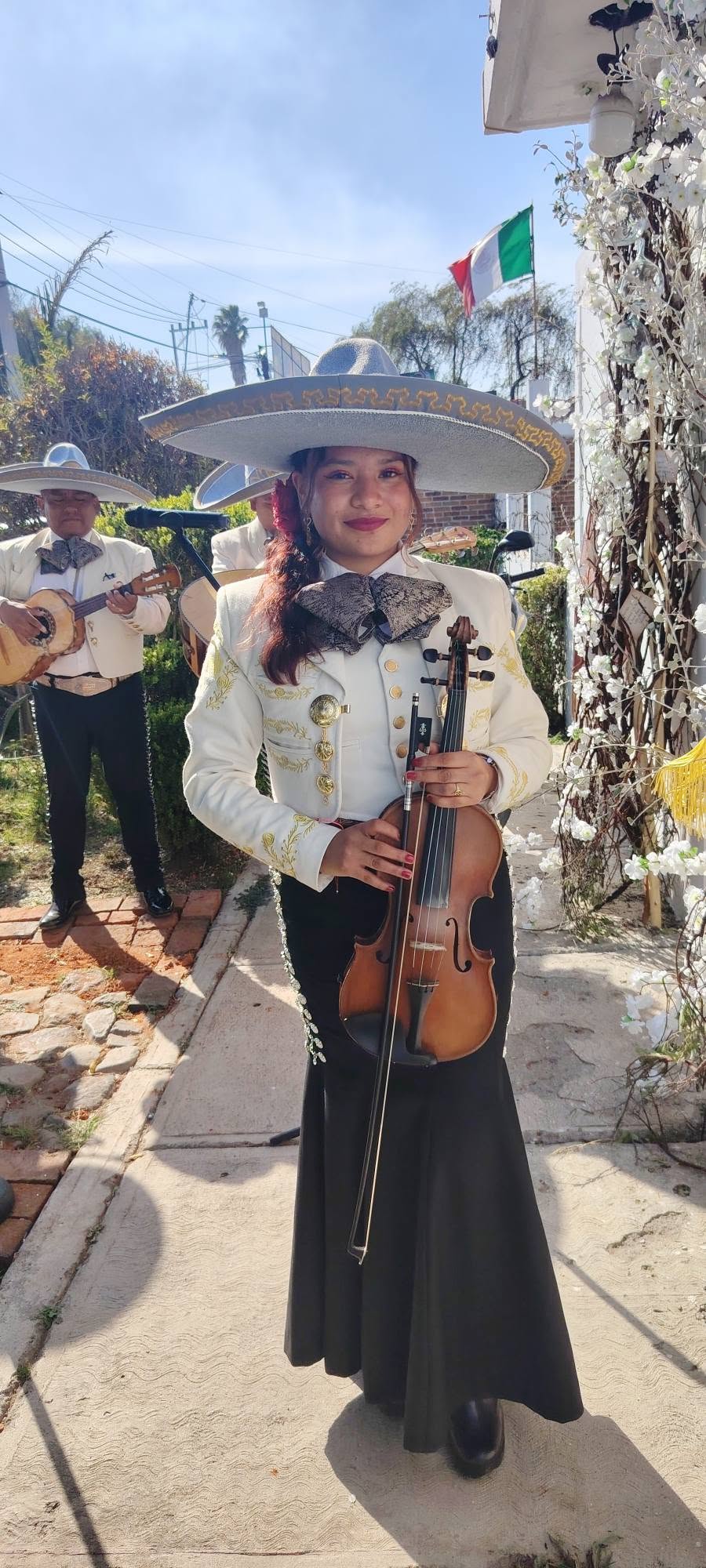 Violinista del mariachi con sombrero charro y traje blanco bordado, lista para una serenata